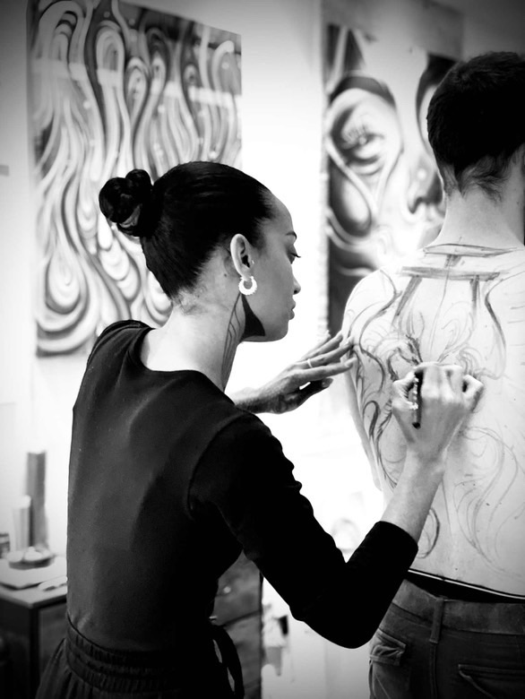 Leali dessine à main levée sur le dos d’une personne pour préparer un tatouage freehand